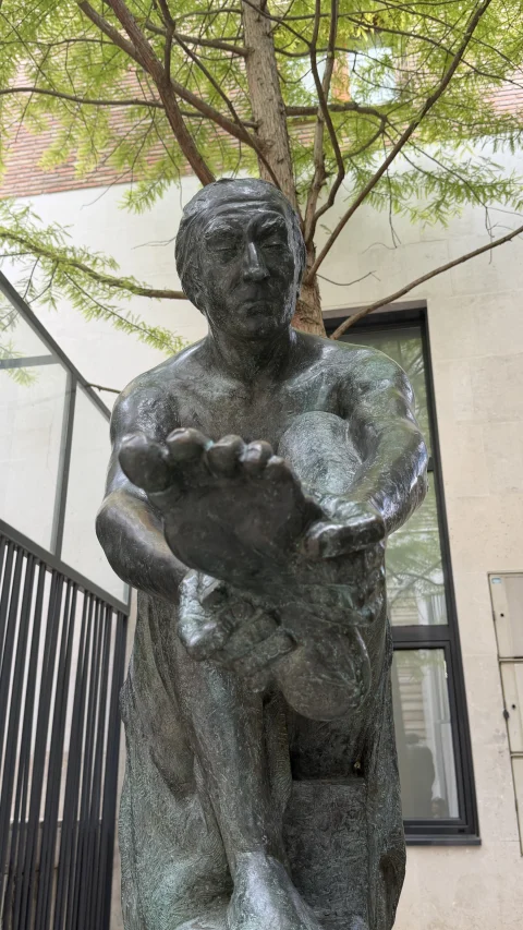 Plano detalle del rostro pensativo y el pie descalzo de la estatua de bronce del peregrino