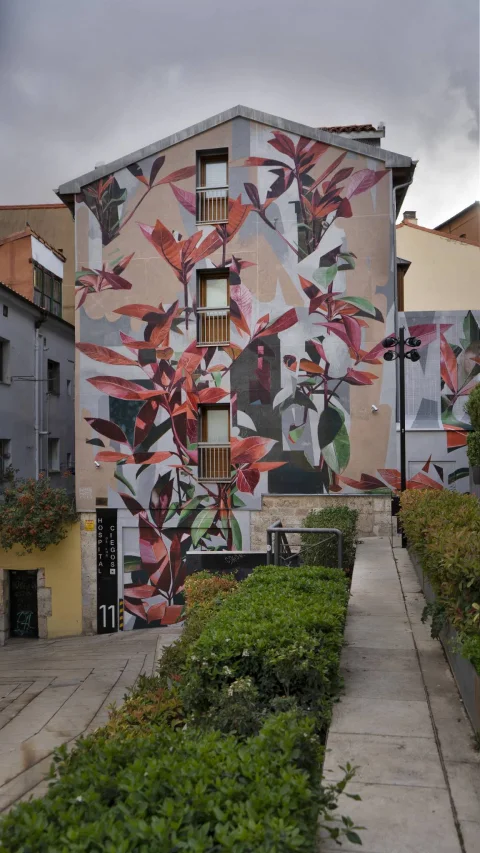 Perspectiva vertical de la fachada ilustrada con el mural botánico Mímesis y jardineras en Burgos