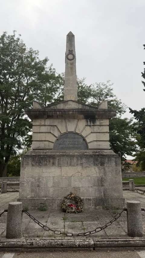 Fachada del monumento con corona de flores en la base