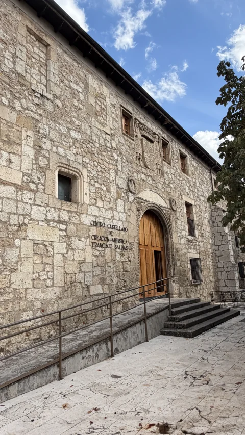 Entrada principal de piedra del Teatro Clunia con rampa de acceso y puerta monumental de madera
