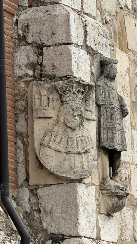 Esculturas de piedra integradas en el muro exterior de sillería del Teatro Clunia