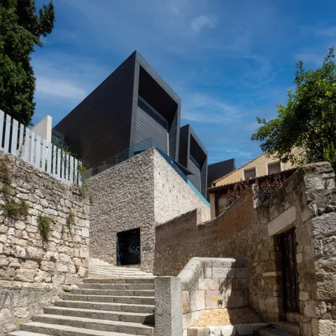 Escalinatas de piedra en primer plano con la arquitectura contemporánea de volúmenes oscuros del centro de arte elevándose al fondo