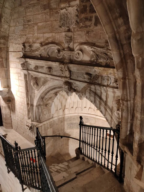 Arco de piedra esculpido con la fecha 1564 y barandilla de forja sobre la escalera de caracol