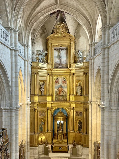 Vista frontal del dorado retablo mayor barroco de San Esteban bajo la bóveda de crucería gótica
