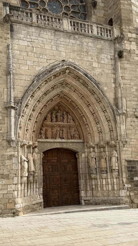 Detalle frontal del pórtico ojival esculpido con figuras de santos en las jambas y relieve del martirio en el tímpano