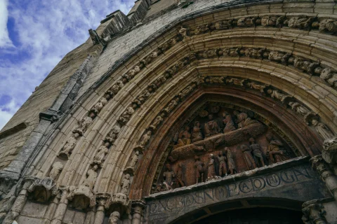 Detalle del tímpano esculpido con el Martirio de San Esteban y las arquivoltas con figuras religiosas en la portada principal gótica