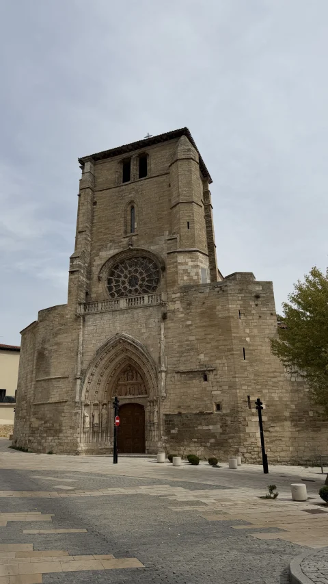 ista frontal completa de la fachada gótica de piedra, mostrando la portada, el rosetón y la torre campanario sobria