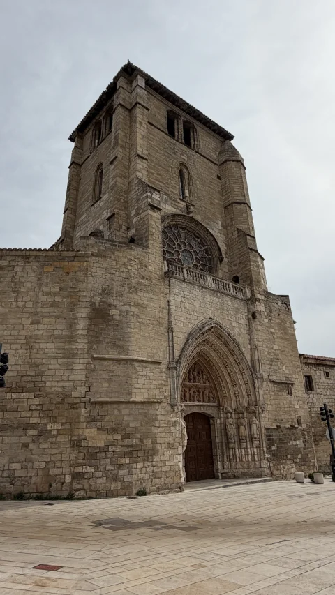 Perspectiva frontal de la imponente fachada gótica con su portalón esculpido, el rosetón superior y la torre prismática de la iglesia