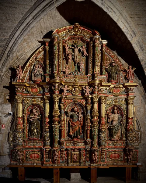 Retablo dorado de estilo barroco con columnas salomónicas y esculturas de santos policromadas