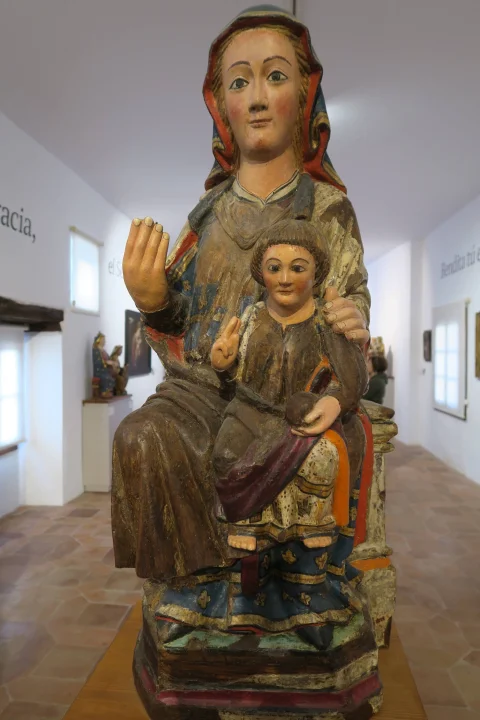 Talla de madera policromada de la Virgen María entronizada sosteniendo al Niño Jesús en actitud de bendecir