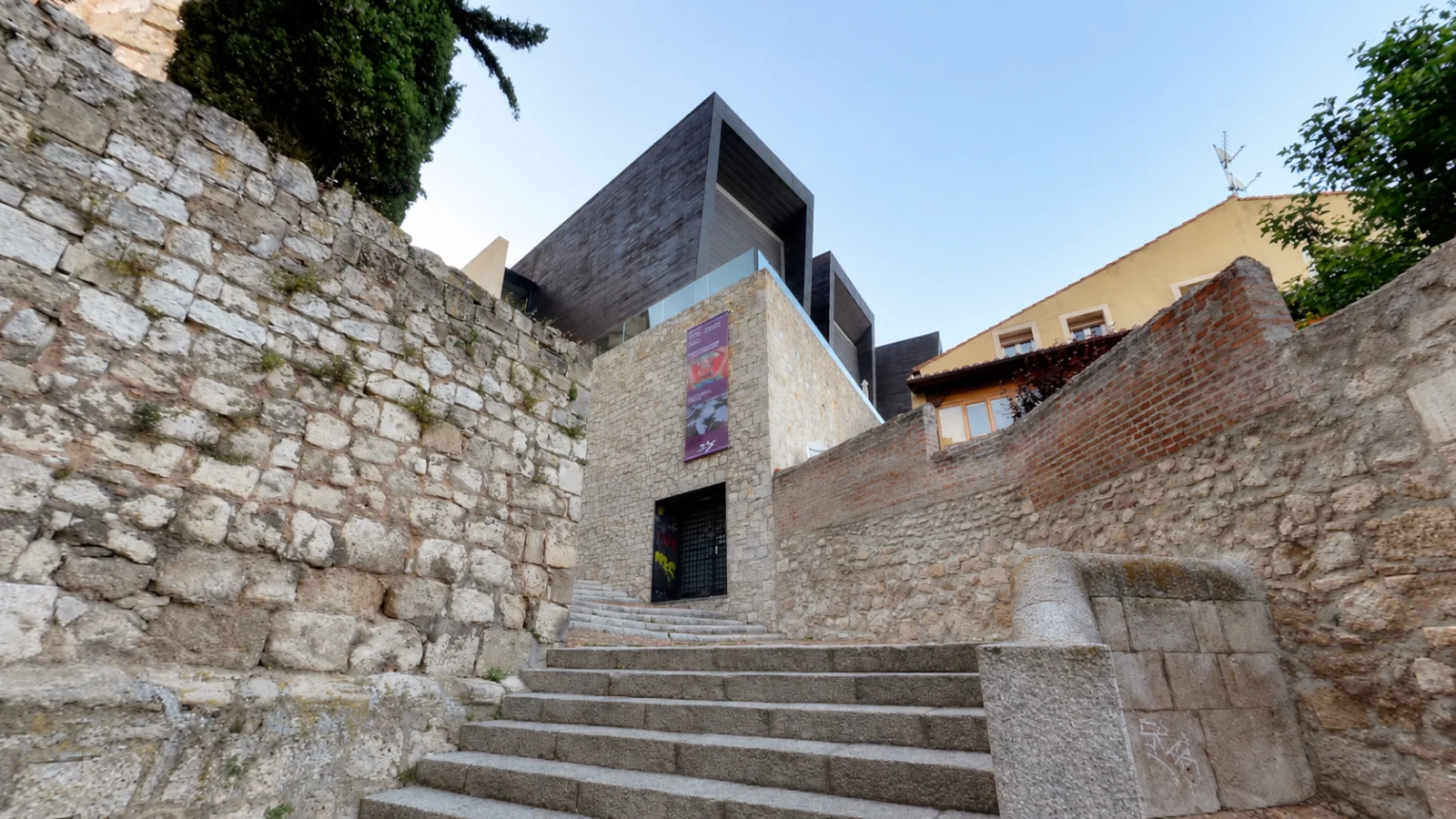 Escalinata de acceso al edificio moderno del CAB entre muros históricos en calle Valentín Palencia