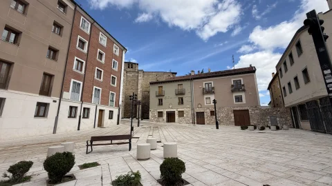 Amplia plaza peatonal con pavimento claro, bancos y viviendas tradicionales en la Calle Pozo Seco