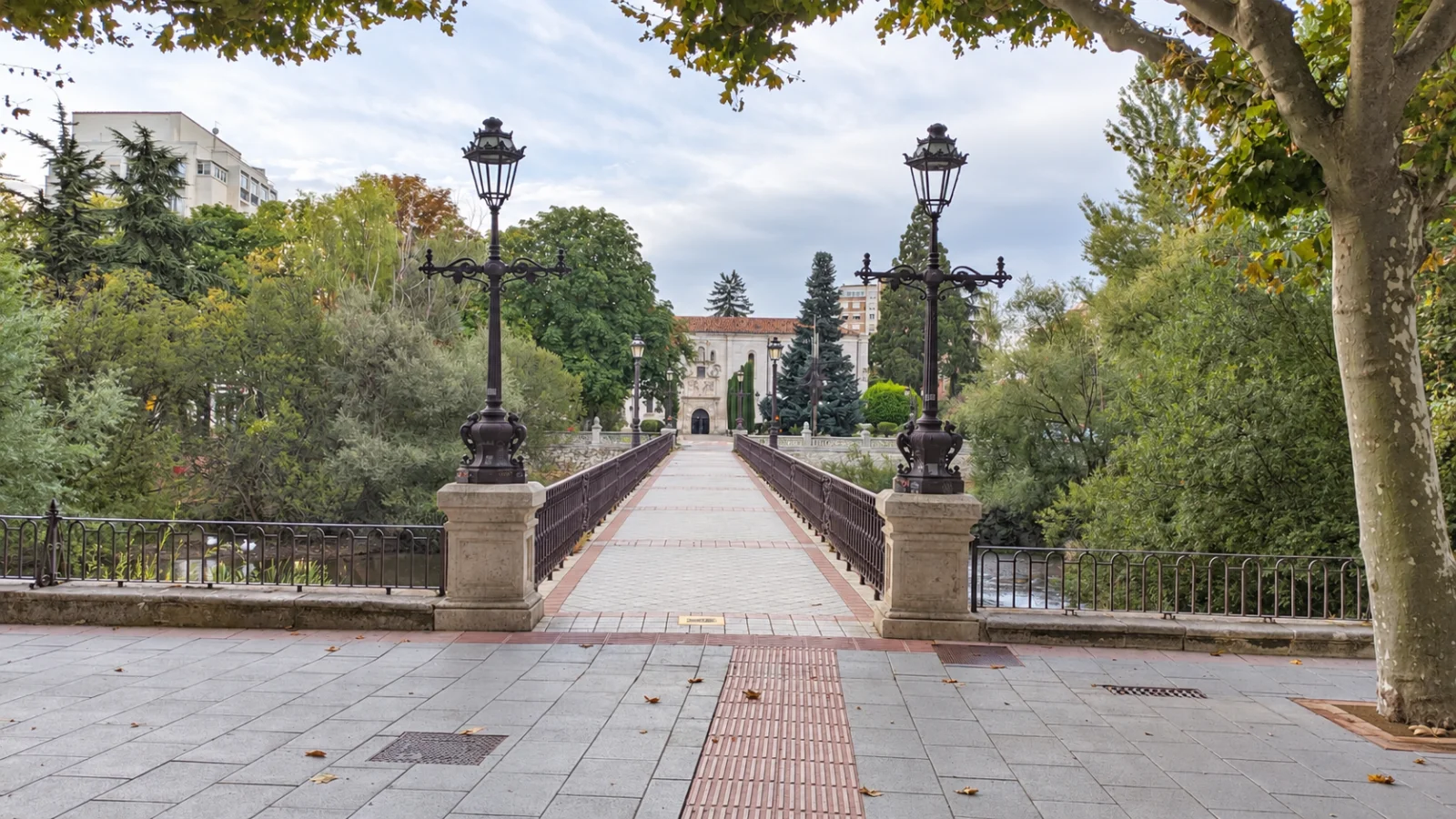 Perspectiva del paso peatonal del Puente de Bessón con farolas de hierro trabajadas en primer plano