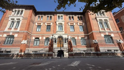 Vista frontal de la fachada principal de ladrillo y piedra del antiguo Colegio del Niño Jesús con reja perimetral de forja