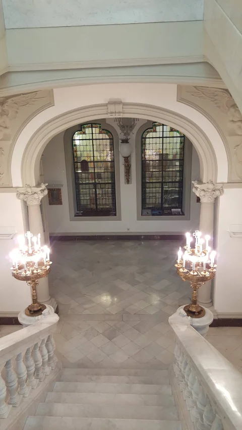 Perspectiva desde arriba de la escalera de mármol con balaustradas y candelabros encendidos en el Palacio Arzobispal