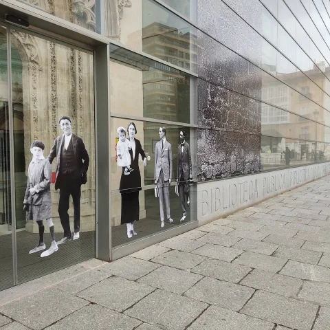 Figuras de fotografías antiguas pegadas en el vidrio de la Biblioteca Pública de Burgos, junto a la entrada