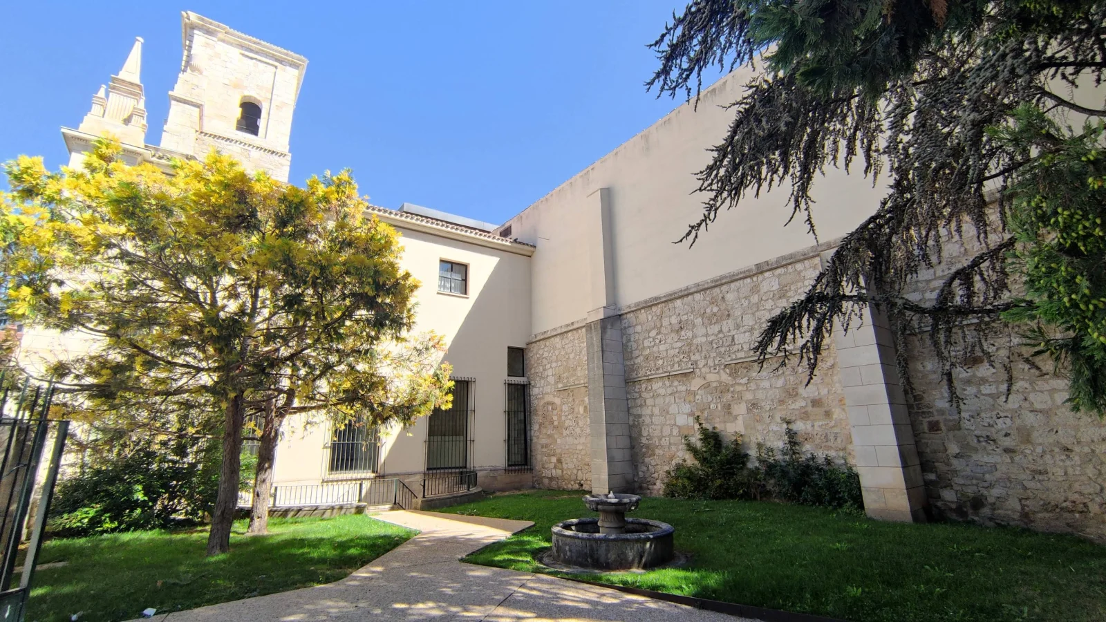 Jardín del Monasterio de San Juan de Burgos, con el pilón de piedra y la espadaña del reloj sobre el muro