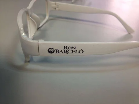 Montura de gafas blanca con la patilla impresa en negro con el logotipo de Ron Barceló
