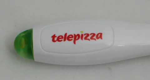 Objeto blanco con tapa verde y el logotipo rojo de Telepizza sobre superficie clara